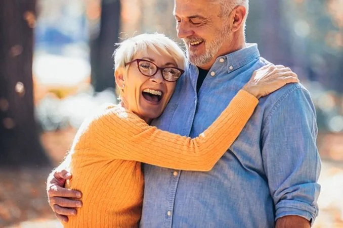 Happy elderly couple embracing outdoors in autumn
